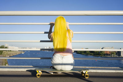 Rear view of yellow umbrella on bridge against sky