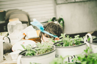 Cropped image of boy wearing headband by potted plants