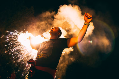 Man with arms outstretched at night