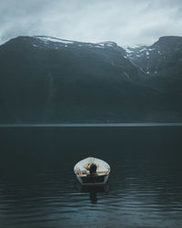 Man in boat on lake against mountain range