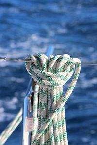 Close-up of ropes tied to railing against sea