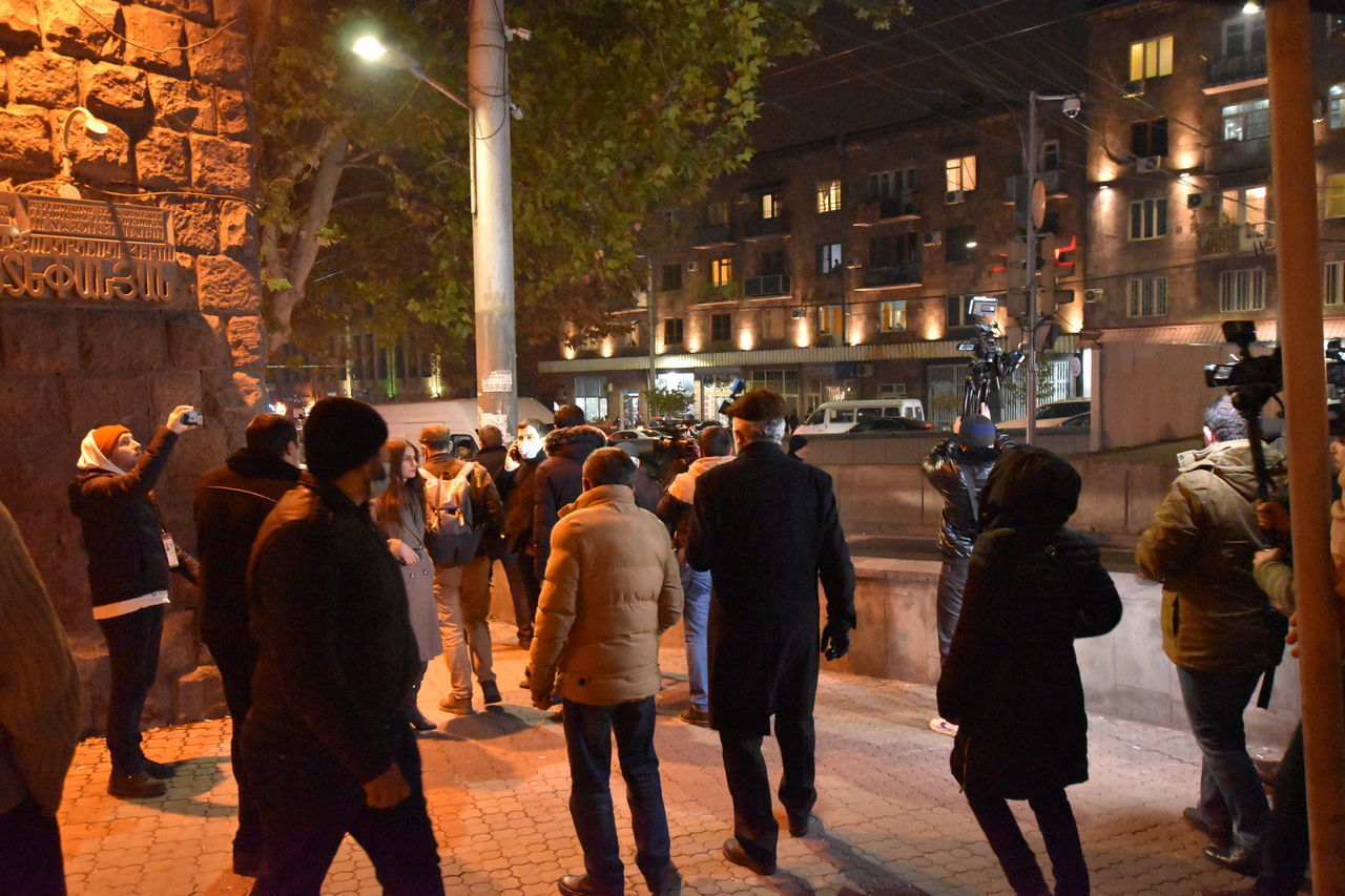 GROUP OF PEOPLE WALKING ON ILLUMINATED STREET AT NIGHT