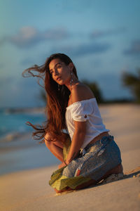 Young woman wearing sunglasses on beach against sky