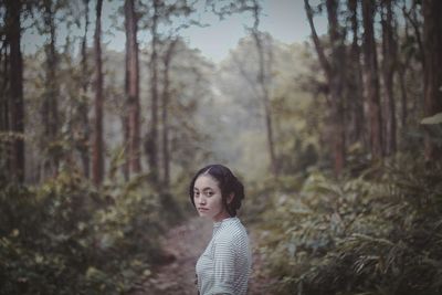 Portrait of young woman standing in forest