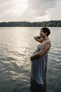 Side view of man standing in lake against sky