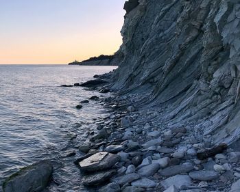 Rock formation on beach against sky during sunset