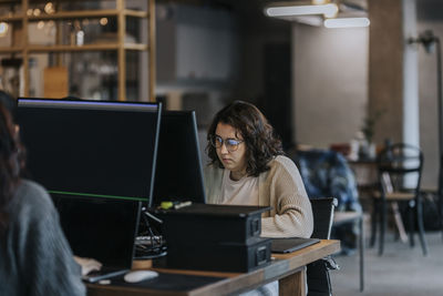 Young female programmers working on computers at desk in startup company