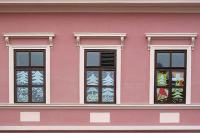 Three windows with christmas painting decoration on the pink wall