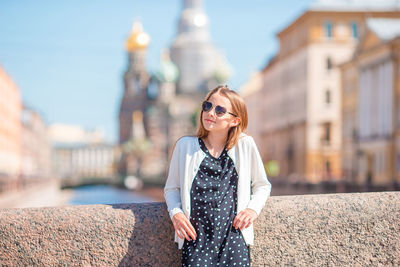 Young woman standing against building in city