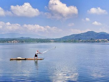 Fisherman throwing fishing net in lake