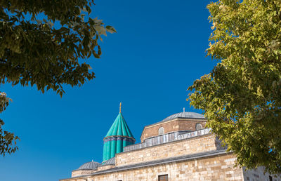 Low angle view of trees and building against blue sky