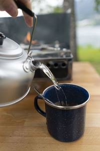 Close-up of hand pouring tea cup on table