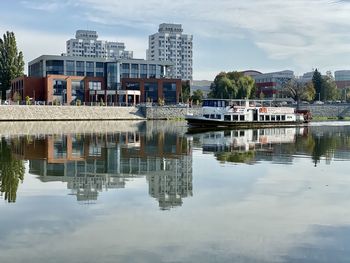 Reflection of buildings in lake against sky in city