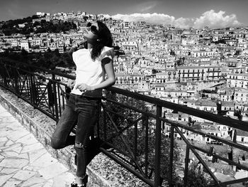 Rear view of woman standing by railing against sky