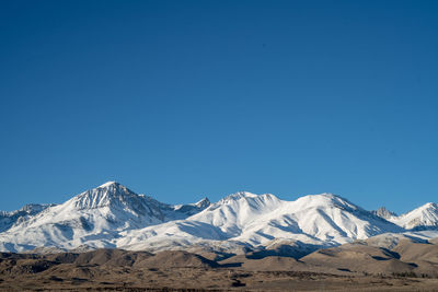 Scenic view of snowcapped mountains against clear blue sky