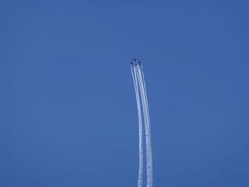 Low angle view of vapor trail against clear blue sky