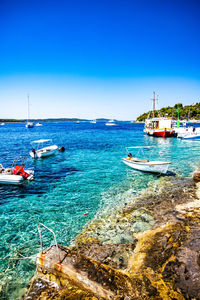 Sailboats moored on sea against blue sky