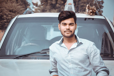 Portrait of young man standing in car