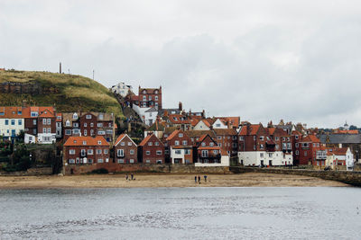 Houses at beach against cloudy sky