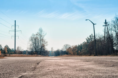 Road amidst trees on field against sky