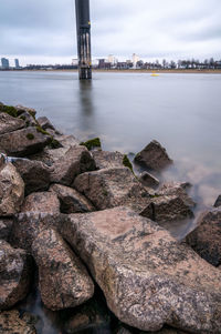 Rocks by river against sky