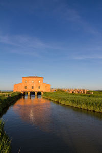 Built structure by lake against blue sky