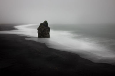 Rock formation on beach against sky