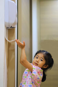 Portrait of cute girl standing against wall