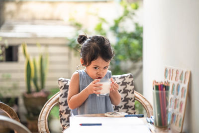 Cute little girl drinking milk at table