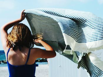 Rear view of woman standing by sea against sky