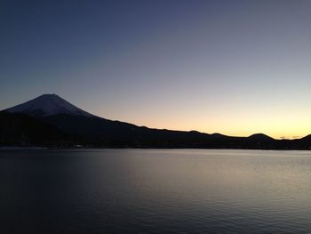 Scenic view of lake by mountains against clear sky