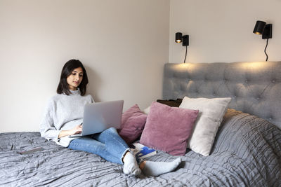 Young woman using laptop on bed