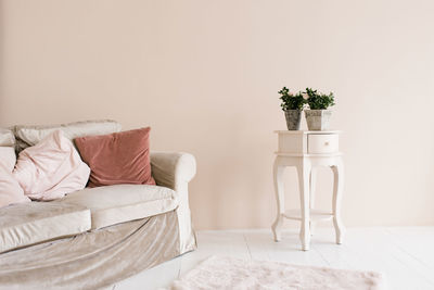 Beige sofa with pink pillows t potted houseplant on the nightstand