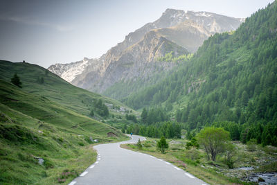 Road amidst green mountains against sky