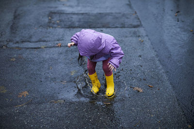 A little girl having fun splashing in puddles on a rainy day.