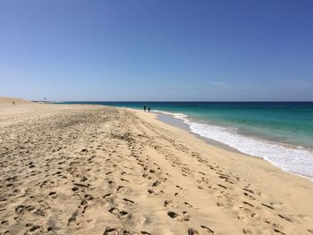 Scenic view of beach against clear blue sky
