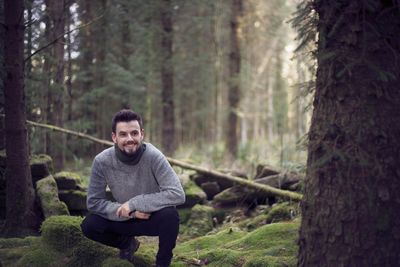Portrait of man sitting on tree trunk