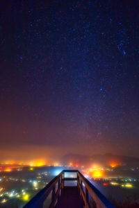 Scenic view of illuminated street against sky at night