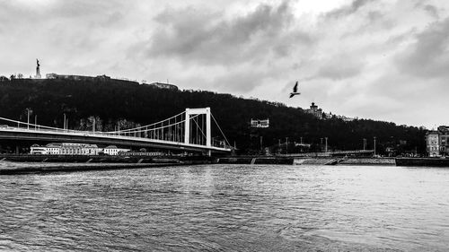 Bridge over river against sky in city