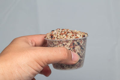 Close-up of person holding ice cream cone against white background