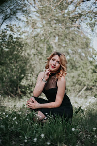 Portrait of beautiful young woman sitting on land