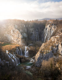 Scenic view of waterfall and mountains against sky