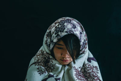 Close-up of young woman against black background