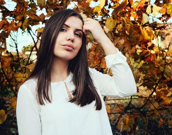 Beautiful young woman standing by tree in park