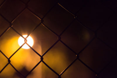 Full frame shot of chainlink fence against sky during sunset