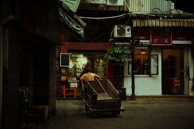 Empty seats on street amidst buildings at night