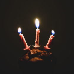Close-up of lit candle against black background