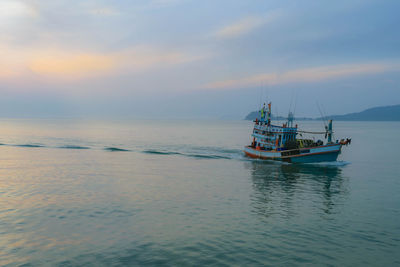 Fishing boat in sea against sky during sunset