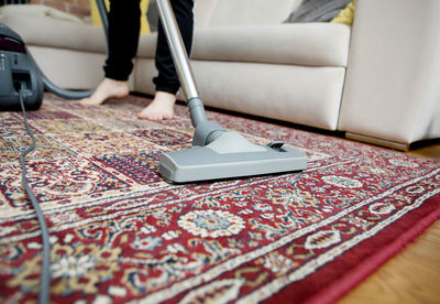 Low section of person using mobile phone on rug at home