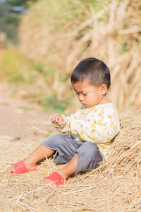 Boy sitting on dried grass